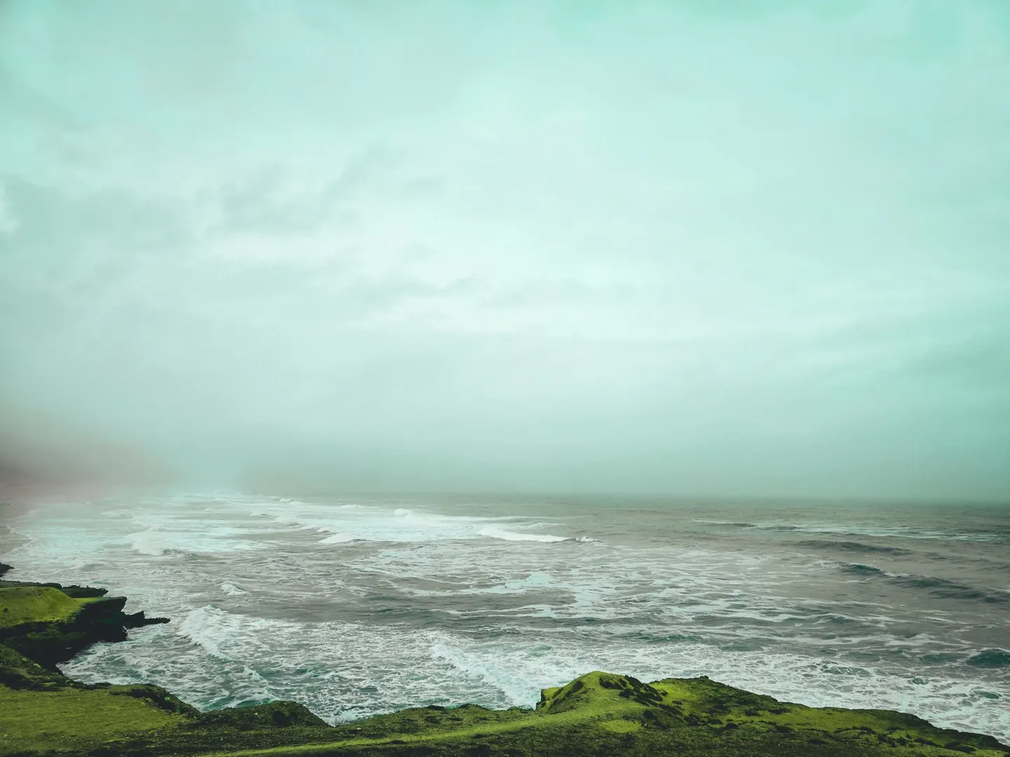 Waves meeting the green rocky shore at Mughsail, Salalah
