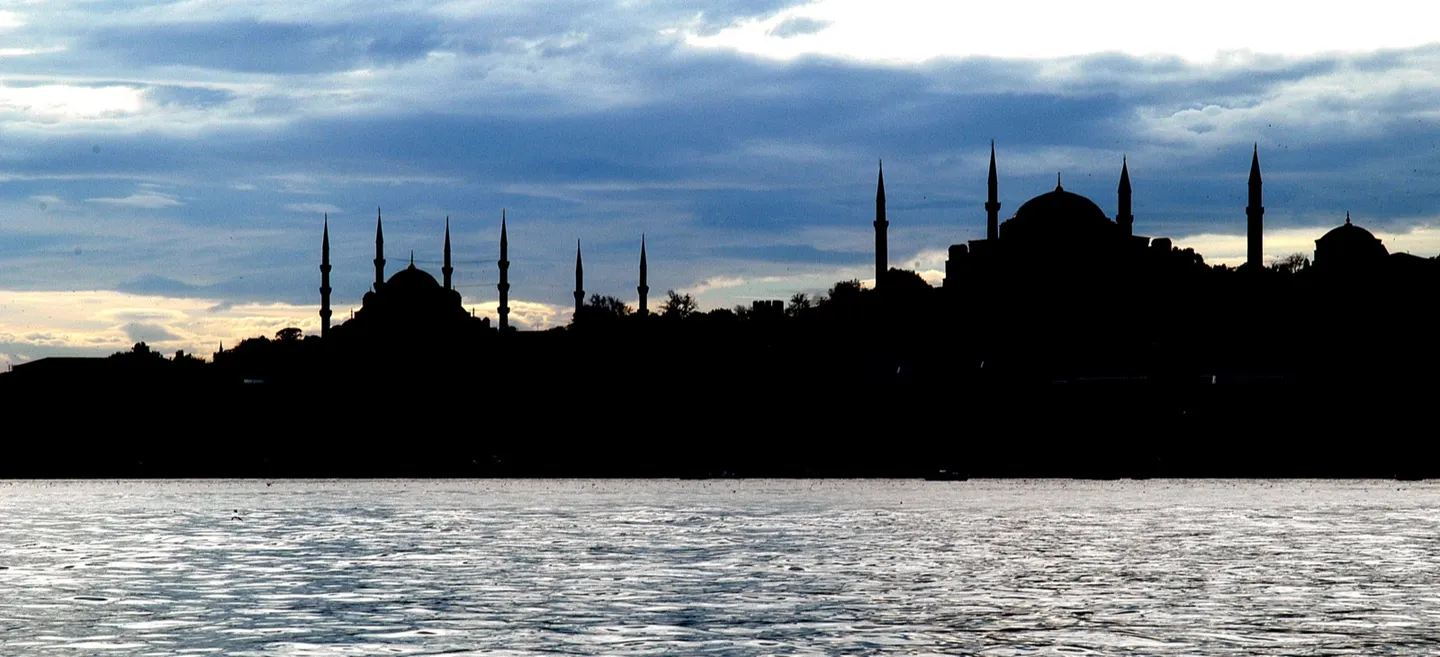Istanbul mosque silhouettes across the water under a cloudy evening sky